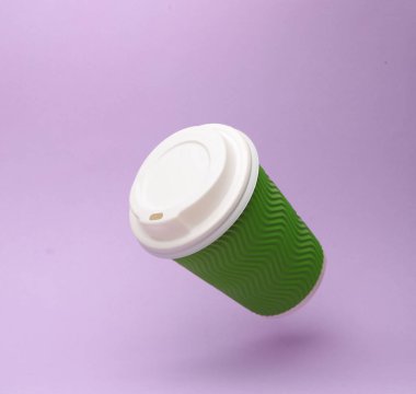 Yeşil kullan-at bardaklar sıcak içecekler için (çay, kahve) lavanta rengi arka planda gölgeli havalanır