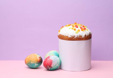 Beyaz etiketli Paskalya pastası ve pastel arka planda renkli yumurtalar. Paskalya 'da hayat. Yaratıcı model