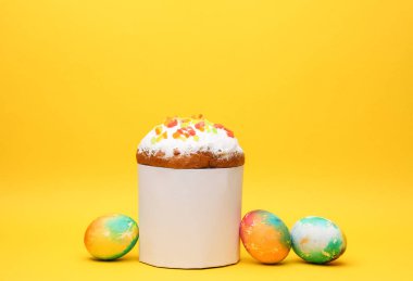 Beyaz etiketli Paskalya pastası ve sarı arka planda renkli yumurtalar. Paskalya 'da hayat