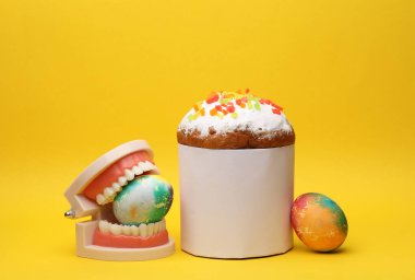 Beyaz etiketli Paskalya pastası, renkli yumurtalar, sarı arka planda çene. Paskalya 'da hayat