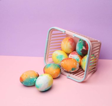 Pastel arka planda Paskalya yumurtaları olan süpermarket sepeti. Minimalizm Paskalyası