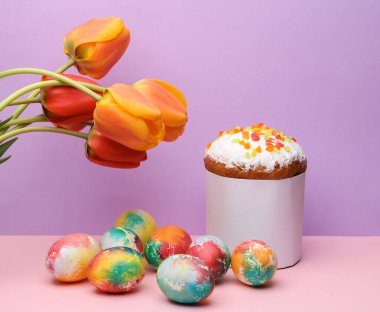 Beyaz etiketli Paskalya pastası ve pastel arka planda laleli renkli yumurtalar. Paskalya 'da hayat