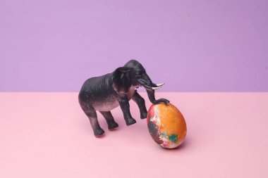 Pastel arka planda renkli yumurtalı bir fil. Kavramsal Paskalya fotoğrafı