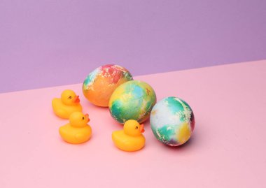 Pastel renkli arka planda Paskalya yumurtası ve lastik ördekler. Minimalizm Paskalyası