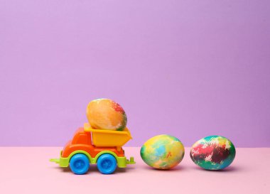 Pastel arka planda Paskalya yumurtaları olan oyuncak kamyonu. Minimalizm Paskalyası