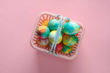 Paskalya yumurtaları ve pembe pastel arka planda süpermarket sepeti. Minimalizm Paskalyası