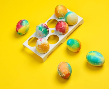 Sarı arka planda renkli Paskalya yumurtaları..