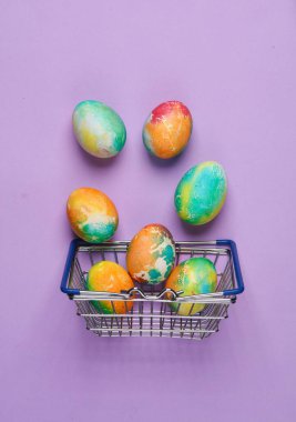 Pastel arka planda Paskalya yumurtaları olan süpermarket sepeti. Minimalizm Paskalyası