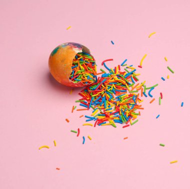 Renkli paskalya şekeri, pembe arka planda yumurta serpiştirilmiş. Yaratıcı Paskalya düzeni
