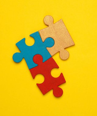 Sarı arkaplandaki renkli yapboz parçacıkları. İş konsepti