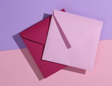 Pastel arka planda iki pembe kare zarf.