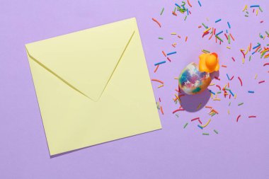 Zarf, renkli paskalya şekeri ve mor arka planda ördek yumurtası. Yaratıcı Paskalya düzeni