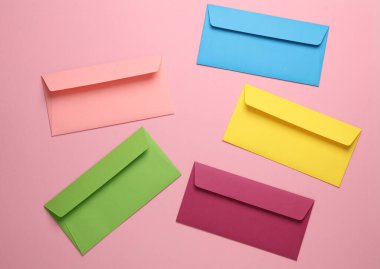 Pembe arka planda bir grup renkli zarf. Yaratıcı yerleşim