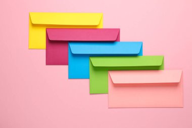 Pembe arka planda bir grup renkli zarf. Yaratıcı yerleşim