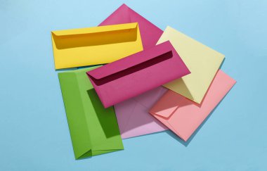 Mavi arkaplanda renkli zarflar var. Yaratıcı yerleşim