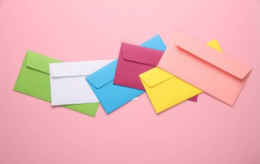 Pembe arka planda renkli zarflar. Yaratıcı yerleşim