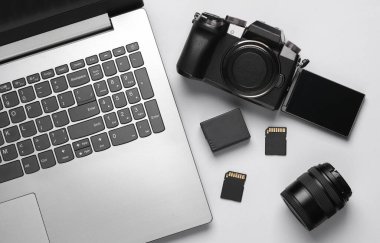 Laptop, ters ekran ile modern dijital kamera, iki SD- hafıza kartı, gri arka planda pil ve lens. Fotoğrafçı ekipmanı. Üst Manzara. Düz yatıyordu