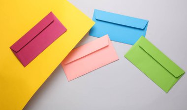 Sarı arkaplanda renkli zarflar var.