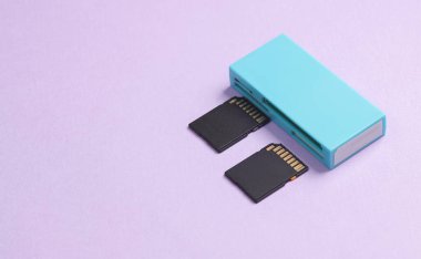 Pastel mor arka planda iki SD hafıza kartı olan kart okuyucu