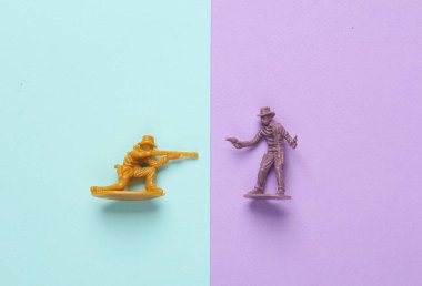 Pastel arka planda plastik kovboylar. Vahşi batı, batı. Minimalizm