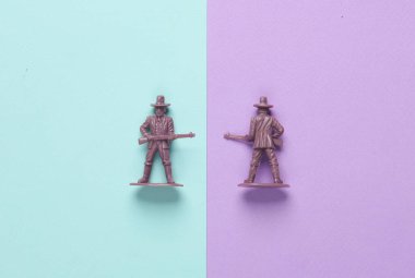 Pastel arka planda plastik kovboylar. Vahşi batı, batı. Minimalizm