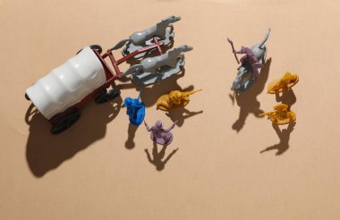 Vahşi batı sahnesi. Plastik kovboy ve bej arka planda Amerikan Kızılderili çatışması