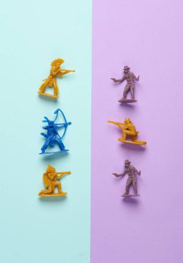 Vahşi batı sahnesi. Pastel arka planda plastik kovboy ve Amerikan kızılderili çatışması