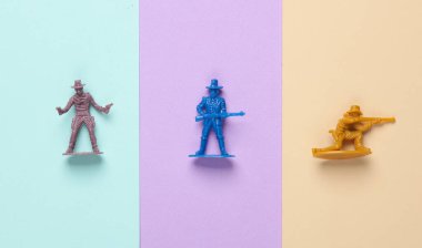 Pastel arka planda plastik kovboylar. Vahşi batı, batı. Yaratıcı yerleşim