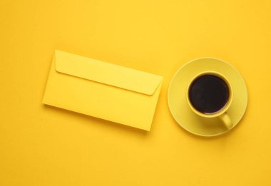 Sarı arkaplanda kahve ve zarf bulunan sarı seramik bardak. Üst görünüm