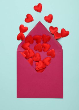 Mavi zemin üzerinde kırmızı kalpler olan bir zarf. Sevgililer Günü, aşk konsepti.