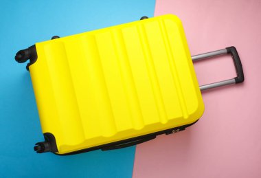 Sarı tekerlekli bavul, seyahat çantası ya da pembe mavi arka planda valiz. Yaz tatili, seyahat, gezi konsepti. Üst görünüm