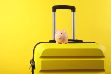 Sarı plastik bir çantada kumbarası ve sarı bir arka planı var. Seyahat bütçesi