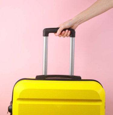 El ele tutuşarak pembe arka planda sarı plastik bir valiz taşıyorlar. Turizm, tatil kavramı