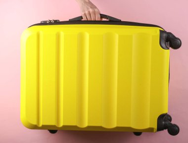 El ele tutuşarak pembe arka planda sarı plastik bir valiz taşıyorlar. Turizm, tatil kavramı