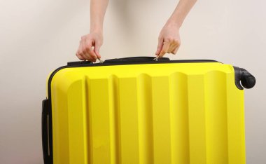 El açık sarı plastik valiz beyaz arka planda. Turizm, tatil kavramı