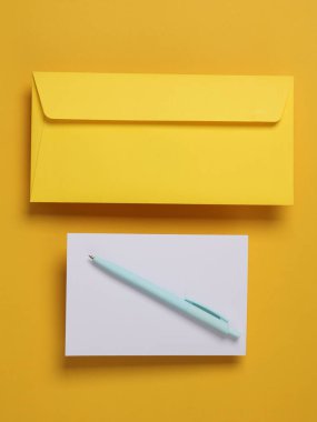 Sarı zemin üzerinde beyaz boş tebrik kartı olan sarı zarf.