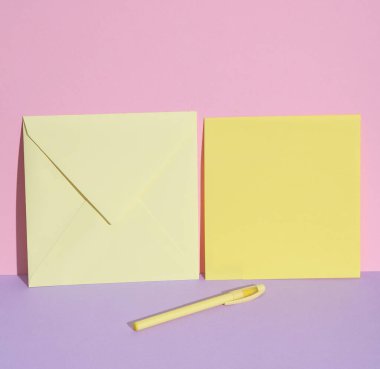 Pastel arka plan üzerinde harf ve kalem olan sarı zarfın yaratıcı düzeni