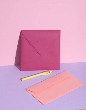 Pastel arka planda pembe ve mor zarflı yaratıcı bir düzen.. 