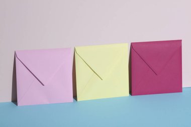 Pastel parlak arkaplanda renkli zarflar olan yaratıcı bir düzen. Minimalizm