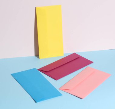 Pastel parlak arkaplanda renkli zarflar olan yaratıcı bir düzen. Minimalizm