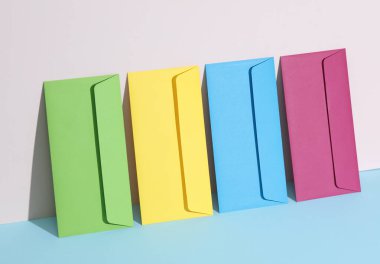 Pastel parlak arkaplanda renkli zarflar olan yaratıcı bir düzen. Minimalizm