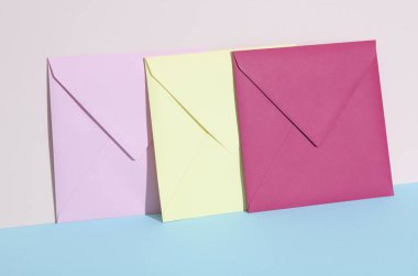 Pastel parlak arkaplanda renkli zarflar olan yaratıcı bir düzen. Minimalizm