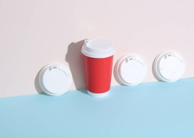 Sıcak içecekler için beyaz kapaklar ve pastel arka planda gölgeli karton bardak. Yaratıcı düzen, minimalizm