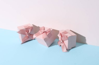 Kavramsal tatil fotoğrafı. Pastel arka planda gölgeli pembe hediye kutuları