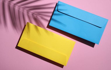 Pembe arka planda iki zarf ve palmiye yaprağı gölgesi. Minimum yaz konsepti. Üst görünüm