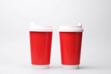 Beyaz arka planda kapaklı kırmızı karton kahve fincanları.