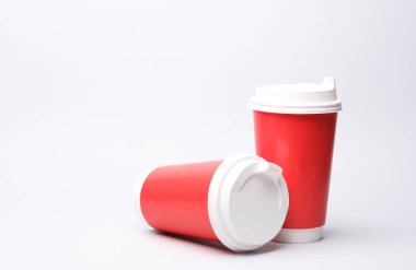 Beyaz arka planda kapaklı kırmızı karton kahve fincanları.