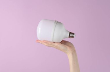 Elektrik tasarrufu. Mor arkaplanda büyük bir ampul var.