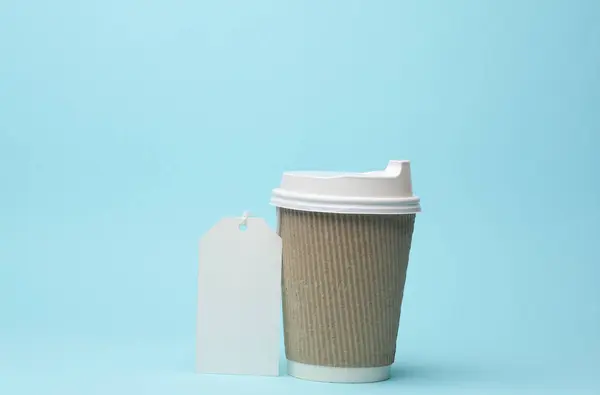 Disposable coffee cup with prise tag isolated on blue background. Template for branding