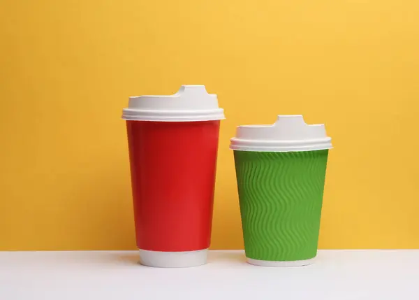 Red and green disposable cups on yellow-white background
